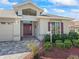 Close-up of home exterior with a brick driveway, mature landscaping, and a front door with address signage at 17504 Se 119Th Cir, Summerfield, FL 34491