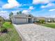 Charming home with a brick driveway, lush green lawn, mature landscaping, and a two-car garage at 17504 Se 119Th Cir, Summerfield, FL 34491