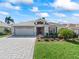 Inviting home with a brick driveway, lush green lawn, mature landscaping, and a two-car garage at 17504 Se 119Th Cir, Summerfield, FL 34491