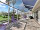 Inviting screened lanai with outdoor seating, grill, and view of the lush green backyard, perfect for relaxing at 17504 Se 119Th Cir, Summerfield, FL 34491