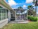 Exterior view of the screened lanai, featuring outdoor seating, a grill, and access to the well-maintained backyard at 17504 Se 119Th Cir, Summerfield, FL 34491