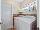 Functional laundry room with modern washer and dryer units, shelving, and a patterned accent wall at 17504 Se 119Th Cir, Summerfield, FL 34491
