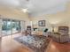 Bright living room featuring vaulted ceilings, hardwood floors, area rug, and sliding doors to lanai at 17504 Se 119Th Cir, Summerfield, FL 34491