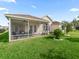 Backyard view shows screened-in patio with lush lawn and tasteful landscaping at 1904 Augustine Dr, The Villages, FL 32159