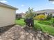 View of the landscaped backyard with stamped concrete and a covered barbecue grill at 1904 Augustine Dr, The Villages, FL 32159