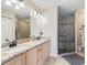 Bathroom featuring double sinks with granite countertops, a large mirror, and a glass-enclosed shower at 1904 Augustine Dr, The Villages, FL 32159