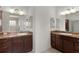Bathroom featuring dual vanities, warm lighting, and mirrors at 1938 Sassparilla Way, The Villages, FL 32162