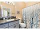 Bright bathroom with a gray vanity, toilet, and shower with a decorative shower curtain at 1952 Peachtree Ave, The Villages, FL 32162