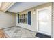 Inviting front entrance with patterned concrete and a white front door, complemented by blue shutters and a wall lamp at 2116 Baldwin Run, The Villages, FL 32162