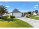Landscaped front yard with a unique concrete driveway leading to a well-maintained single-story house and attached garage at 2116 Baldwin Run, The Villages, FL 32162