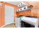 Well-organized laundry room featuring washer, dryer, storage shelves and orange walls at 2116 Baldwin Run, The Villages, FL 32162