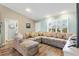 Comfortable living room with a large sectional sofa, wood floors, and a view of the front yard through shuttered windows at 2116 Baldwin Run, The Villages, FL 32162