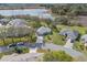 Aerial view of a single-story home with a well-manicured lawn near a lake, as well as neighborhood views at 21902 King Henry Ave, Leesburg, FL 34748