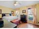 Bright bedroom features hardwood floors, neutral walls, two windows, a ceiling fan, and a chest at 21902 King Henry Ave, Leesburg, FL 34748