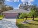 Charming home exterior featuring a lush front lawn, mature palms, and a clean driveway on a sunny day at 21902 King Henry Ave, Leesburg, FL 34748