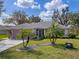 Charming single-story home showcasing a manicured lawn, mature palm trees, and a welcoming front entrance at 21902 King Henry Ave, Leesburg, FL 34748