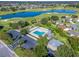 Aerial view of community pool surrounded by lounge chairs, parking, a golf course, and a beautiful lake at 2195 Marlboro St, The Villages, FL 32162