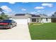 Single-story home with a two car garage, stone accents and lush lawn at 22325 Sw Nectarine Ln, Dunnellon, FL 34431