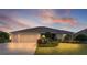 Lovely single-story home featuring a well-manicured lawn and an attached two-car garage at dusk at 2935 Cedar Grove Loop, The Villages, FL 32163