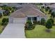 Well-maintained single-story home featuring an attached three-car garage, manicured lawn, and mature landscaping at 2935 Cedar Grove Loop, The Villages, FL 32163