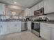 Well-lit kitchen with stainless steel appliances, white cabinets, and neutral countertops at 3067 Southern Trce, The Villages, FL 32162