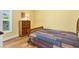 Bedroom with wood floors and bed with colorful quilt next to a wooden dresser at 3233 Belcherry Loop, The Villages, FL 32163