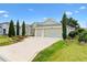 View of a single-story house, showing its manicured lawn, mature landscaping, and three-car garage at 3233 Belcherry Loop, The Villages, FL 32163