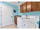 Laundry room with blue walls, tile flooring, a door, and a sink and a washing machine at 3233 Belcherry Loop, The Villages, FL 32163