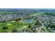 Expansive aerial view showcases a residential area bordering a golf course and a serene lake at 3234 Berkeley Ln, The Villages, FL 32162
