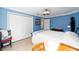 This bedroom features blue walls, a large closet, an overhead fan, and neutral tile floors at 3234 Berkeley Ln, The Villages, FL 32162