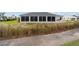 A ground-level view of the back of a home with a screened lanai, overlooking a well-maintained lawn and lush vegetation at 3234 Berkeley Ln, The Villages, FL 32162