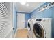 A laundry room featuring front-load washer and dryer, blue walls, tile floors, and a door with louvered slats at 3234 Berkeley Ln, The Villages, FL 32162