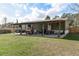 Home exterior featuring covered patio, a green lawn, and dark wooden fence surrounding the property at 32904 State Road 44, Deland, FL 32720