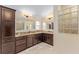 Bathroom with dual sinks, dark wood cabinets, and glass block window at 3342 Queensway Ter, The Villages, FL 32163