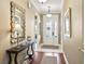 Inviting entryway with decorative mirror, table, and white front door with glass panels and transom window at 3654 Enterprise Dr, The Villages, FL 32163