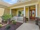 Inviting front porch with a hanging swing, decorative pillars, and a beautifully decorated front door at 3654 Enterprise Dr, The Villages, FL 32163