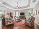 Comfortable living room with hardwood floors, tray ceiling, fan, and large screen television with lots of natural light at 3654 Enterprise Dr, The Villages, FL 32163