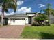 Charming home featuring a brick driveway, two-car garage, stone accents, and lush landscaping with beautiful palm trees at 384 Summer Squall, Davenport, FL 33837