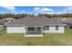 Back exterior view of a single-story home with a covered patio and well-maintained lawn at 4000 Se 98Th Pl, Belleview, FL 34420