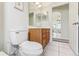 Bathroom offering a toilet and wood-finish vanity with a neutral tile floor, as well as light fixtures above the mirrors at 5135 Aurora Dr, Leesburg, FL 34748