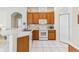 Bright kitchen with wooden cabinets, white appliances, and a tiled floor at 5135 Aurora Dr, Leesburg, FL 34748