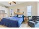 Comfortable main bedroom featuring a cozy armchair, neutral carpeting, and natural light from two sunny windows at 5135 Aurora Dr, Leesburg, FL 34748