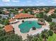 Aerial view of a luxurious cloverleaf-shaped community pool with palm trees and lounge chairs at 5466 Compass Pt # 101, Oxford, FL 34484