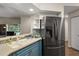 Well-lit kitchen features stainless steel fridge, updated counters, and is open to the living room at 5466 Compass Pt # 101, Oxford, FL 34484