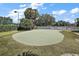 A putting green with manicured artificial turf and mature tree surround in a residential community at 5466 Compass Pt # 101, Oxford, FL 34484