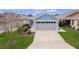 Well-maintained home with a two-car garage, green lawn, and manicured landscaping at 5934 Kaplan Ct, The Villages, FL 32163