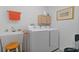 Modern laundry room featuring a washer, dryer, utility sink, cabinet, and orange accents at 5934 Kaplan Ct, The Villages, FL 32163