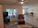Cozy living room featuring a comfortable armchair and a view into the dining area with a ceiling fan at 7133 Sw 135Th Pl, Ocala, FL 34473