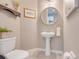 Stylish half-bathroom with pedestal sink, round mirror, and neutral color palette at 831 Zeek Ridge Ct, Clermont, FL 34715