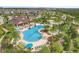 An aerial photograph showcases the community pool with lounge seating, tables, shade umbrellas, and lush tropical landscaping at 831 Zeek Ridge Ct, Clermont, FL 34715